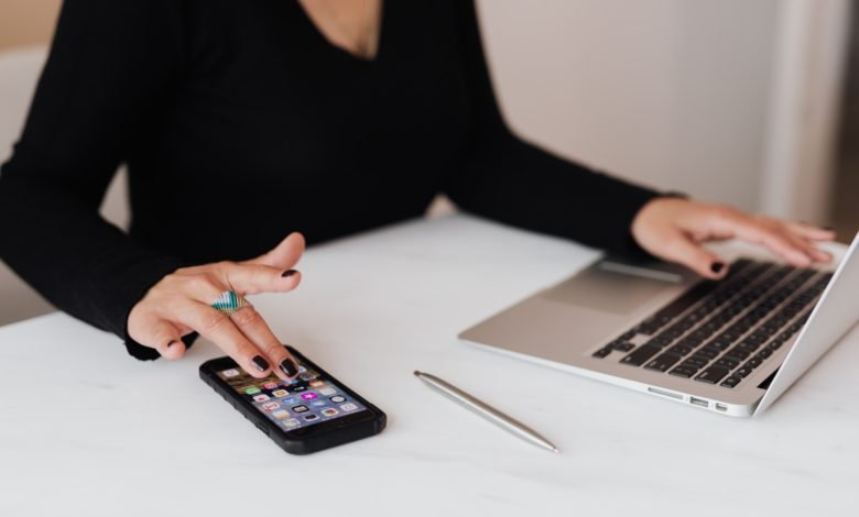 woman using a phone and a laptop